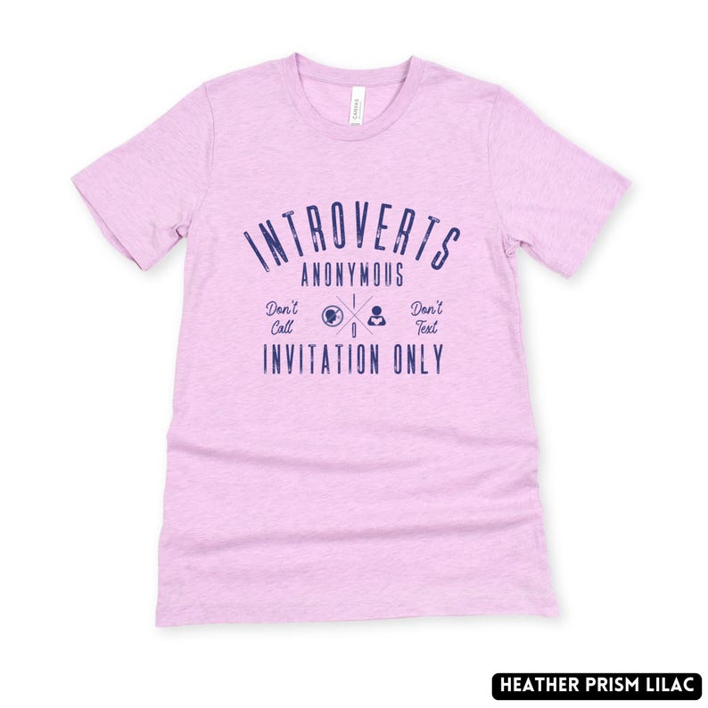 May include: A lilac t-shirt featuring the navy blue text "Introverts Anonymous". The design includes the phrases "Don't Call, Invitation Only, Don't Text". The shirt is made of a soft material.