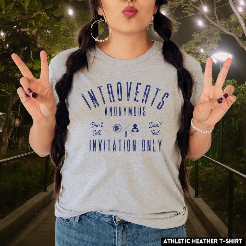 May include: A light grey athletic heather t-shirt with the words "Introverts Anonymous" in dark blue. The shirt also features the phrases "Don't Call, Don't Text, Invitation Only" in dark blue. The t-shirt is made of a soft, comfortable material.