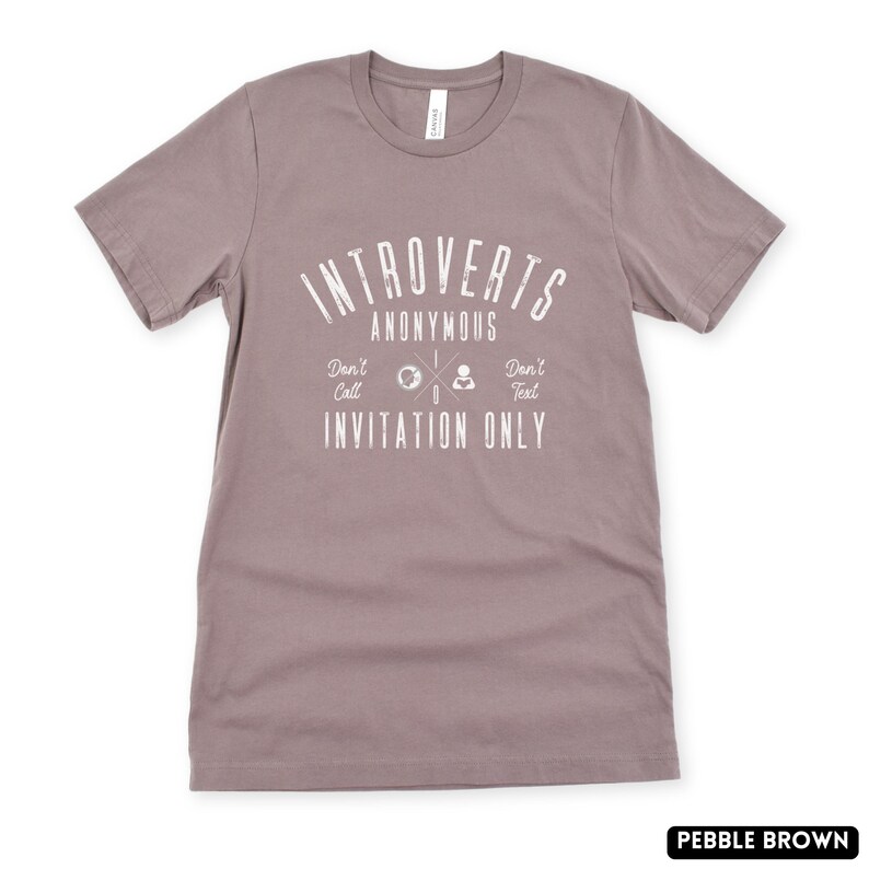 May include: Pebble brown t-shirt featuring the white text "Introverts Anonymous". Below, the shirt reads "Don't Call, Invitation Only, Don't Text". The t-shirt is a crew neck style and is made of a soft material.