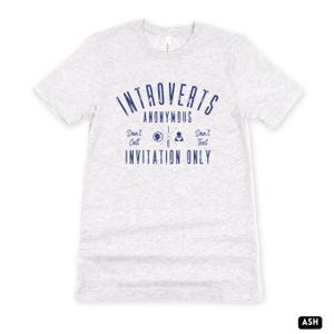 May include: Pale grey t-shirt with navy blue text reading "Introverts Anonymous", accompanied by "Don't Call" and "Don't Text". A graphic with a globe, phone, and text icon is included. The words "Invitation Only" are printed below the graphic.