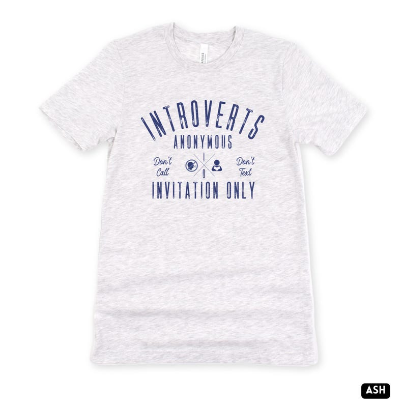 May include: Pale grey t-shirt with navy blue text reading "Introverts Anonymous", accompanied by "Don't Call" and "Don't Text". A graphic with a globe, phone, and text icon is included. The words "Invitation Only" are printed below the graphic.