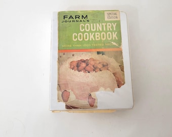 May include: A vintage cookbook titled "Farm Journal's Country Cookbook" with a special edition label. The cover features a photo of a cake topped with strawberries and coconut flakes.