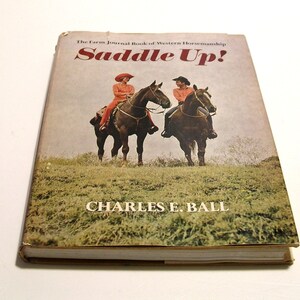May include: A vintage book titled "The Farm Journal Book of Western Horsemanship Saddle Up!" by Charles E. Ball. The cover features a color photograph of two people riding horses in a field.