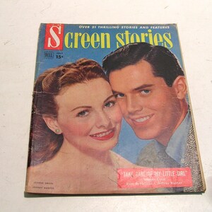 May include: A vintage July issue of "Screen Stories" magazine featuring a color portrait of a smiling woman and man. The magazine cover includes the text "OVER 21 THRILLING STORIES AND FEATURES" and the title "Screen Stories". The magazine also features the text "TAKE CARE OF MY LITTLE GIRL".