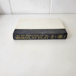 May include: A black hardcover book with gold lettering on the spine that reads "An Almanac of Words at Play" by "E.B. White".