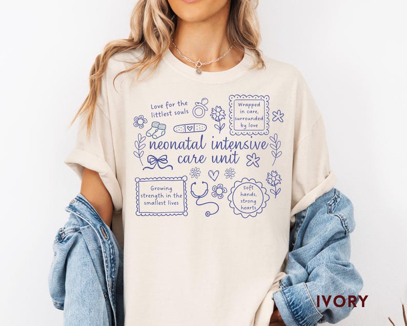 Op de afbeelding: Ivoor kleurig T-shirt met blauwe tekst en illustraties over een neonatale intensive care unit. Het ontwerp bevat zinnen als "Love for the littlest souls" en "Growing strength in the smallest lives."