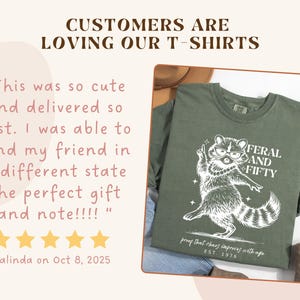 May include: Olive green t-shirt with a white graphic of a raccoon wearing glasses and a pearl necklace, with the text "FERAL AND FIFTY". The shirt also has the text "proof that chaos improves with age" and "EST. 1976".