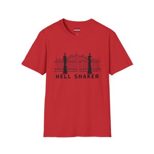Puede incluir: Camiseta roja con un gráfico negro de una puerta y las palabras "HELL SHAKER" impresas debajo. La camiseta es de color rojo sólido y tiene mangas cortas.