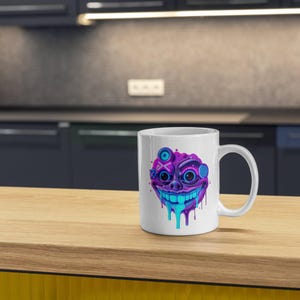 May include: White ceramic mug with a colorful, dripping, cartoon face design. The face is purple, blue, and white with a wide smile and multiple eyes.