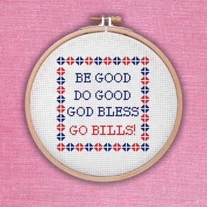 May include: A cross-stitch embroidery hoop with the words "BE GOOD DO GOOD GOD BLESS GO BILLS!" in blue and red thread. The embroidery is on white fabric, framed by a wooden hoop, set against a pink background.
