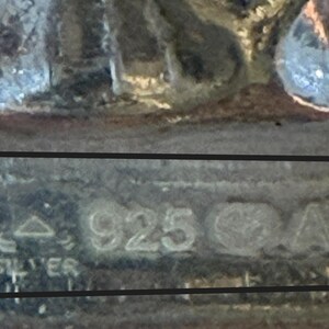 Puede incluir: Primer plano de un objeto de metal plateado con la inscripci&oacute;n "STER 925 CATO" en la parte inferior.