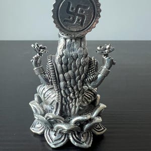 Op de afbeelding: Zilveren beeld van een hindoe&iuml;stische godin die op een lotusbloem zit. De godin draagt een traditionele sari en heeft een halo met een swastika-symbool boven haar hoofd.
