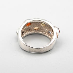 May include: Silver ring with a textured band and multi-colored gemstones.