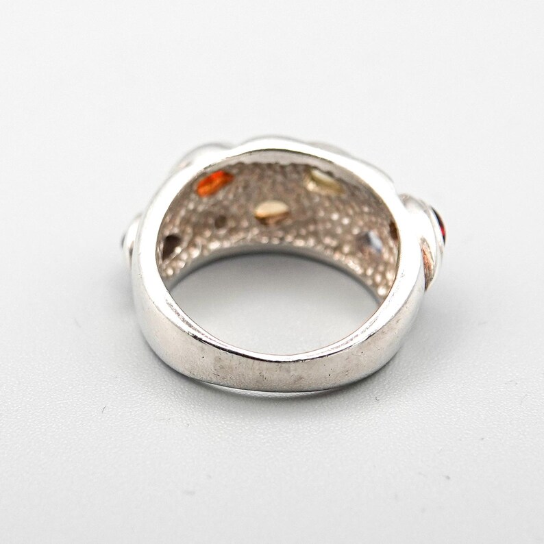 May include: Silver ring with a textured band and multi-colored gemstones.