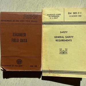 May include: Two vintage manuals. The brown manual, "FM5-34 ENGINEER FIELD DATA," is from June 1956. The yellow manual, "EM 385-1-1 SAFETY GENERAL SAFETY REQUIREMENTS," is dated March 13, 1958. Both manuals are from the U.S. Army.