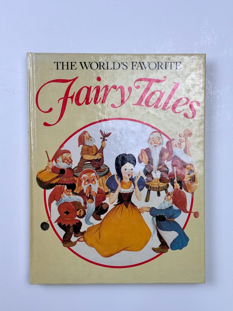 Może przedstawiać: Książka w stylu vintage zatytułowana "The World's Favorite Fairy Tales". Okładka przedstawia ilustrację Kr&oacute;lewny Śnieżki i Siedmiu Krasnoludk&oacute;w w okrągłym wzorze. Tytuł jest w czerwonej, kursywnej czcionce.