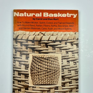 May include: A book titled "Natural Basketry" by Carol and Dan Hart. The cover features a close-up of woven basketry in shades of brown and tan. The book's subtitle details basket-making techniques and materials, including wicker, rattan, and sea grass.