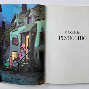 Może przedstawiać: Otwarta książka z kolorową ilustracją z książki dla dzieci Pinokio. Lewa strona przedstawia nocną scenę z budynkiem, postaciami i szyldem gospody. Prawa strona zawiera tytuł "PINOCCHIO".