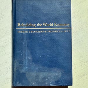 May include: A hardcover book titled "Rebuilding the World Economy" by Norman S. Buchanan & Friedrich A. Lutz. The book has a dark blue cover with gold lettering. The book is slightly worn.