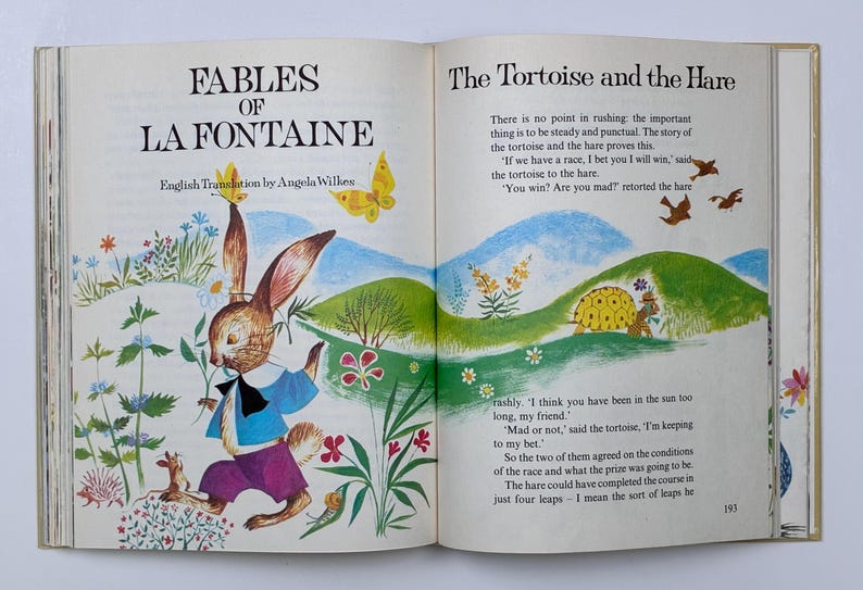 Może przedstawiać: Otwarta książka z kolorowymi ilustracjami z "Bajek La Fontaine'a". Brązowy kr&oacute;lik w niebieskiej koszuli i fioletowych spodniach biegnie przez pole. Na przeciwległej stronie znajduje się ż&oacute;łw i tekst "The Tortoise and the Hare."