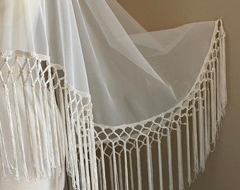 May include: White sheer shawl with a crocheted trim and long fringe. The shawl is draped over a white mannequin.