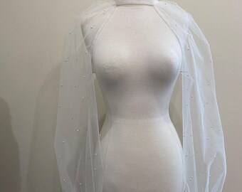 May include: White sheer overlay with long sleeves and a high neck. The sleeves are adorned with small white beads.