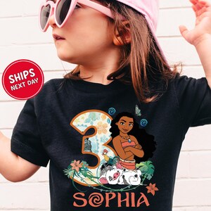 A young girl wearing a black t-shirt with a graphic of a character from the movie "Mulan" and the number 3, along with the text "Sophia".