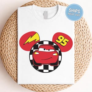A white t-shirt with a graphic design featuring a red car and a lightning bolt, along with the number 95.