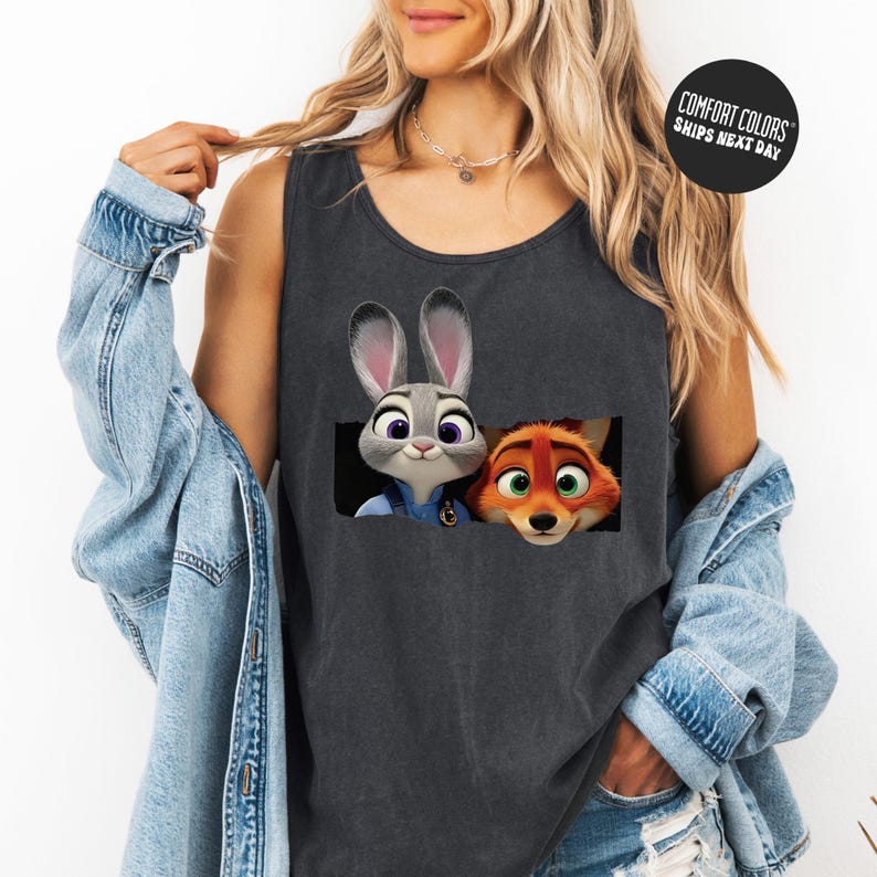 A woman wearing a gray tank top with a graphic of two cartoon animal characters, a rabbit and a fox, peeking out from a hole.