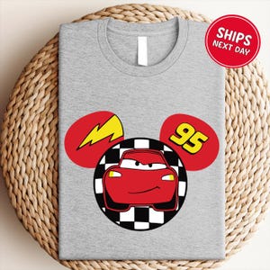 A gray t-shirt with a graphic design featuring a red car and a lightning bolt, along with the number 95.