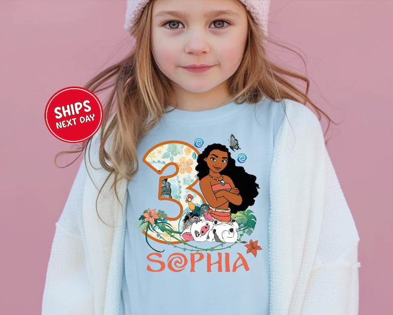 A young girl wearing a t-shirt with a cartoon image of a girl and the number 3, along with the text "Sophia".
