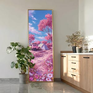 May include: A tall, rectangular framed wall art piece featuring a vibrant landscape illustration. The scene depicts a pink off-road vehicle parked near a tent in a field of colorful wildflowers, surrounded by pink-leafed trees under a blue sky.