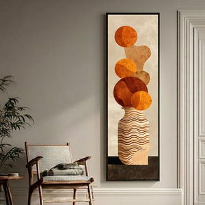 Può includere: Stampa artistica astratta con un vaso con una serie di sfere e forme organiche arancioni. Il vaso ha un design ondulato beige e marrone. L'opera d'arte è incorniciata in una cornice rettangolare nera e appesa a una parete di colore neutro.