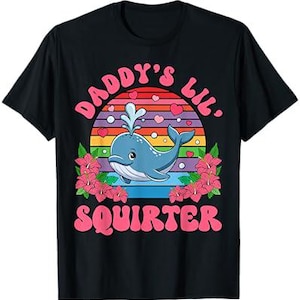 May include: Black t-shirt with a pink and blue graphic of a whale with the text "Daddy's Lil Squirter" in pink.