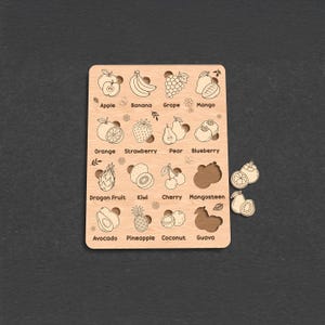 Op de afbeelding: Een houten fruitpuzzel met illustraties van appel, banaan, druif, mango, sinaasappel, aardbei, peer, bosbes, drakenfruit, kiwi, kers, mangosteen, avocado, ananas, kokosnoot en guave. De puzzelstukjes zijn los.