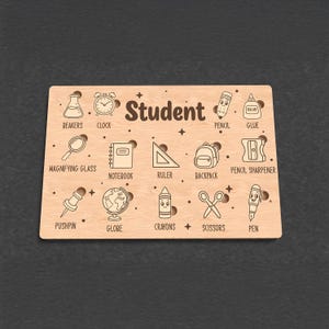 Op de afbeelding: Houten plaat met het woord "Student" en illustraties van schoolspullen, waaronder een klok, potlood, lijm, vergrootglas, notitieboek, liniaal, rugzak, punaise, wereldbol, kleurpotloden, schaar en pen.
