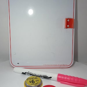 May include: A vintage Coca-Cola sign with the words "PAUSE...DRINK Coca-Cola" in red and white. Includes a marker, bottle caps, and a yellow and red bottle cap with the price $6.00.