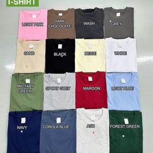 May include: A collection of folded t-shirts in various colors, including light pink, dark chocolate, wash, grey, sand, black, beige, white, military green, sport grey, maroon, light blue, navy, corola blue, ash, and forest green. The word "T-SHIRT" is at the top.