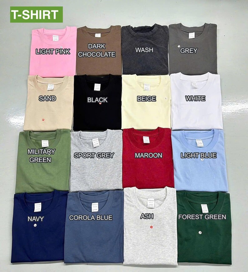 May include: A collection of folded t-shirts in various colors, including light pink, dark chocolate, wash, grey, sand, black, beige, white, military green, sport grey, maroon, light blue, navy, corola blue, ash, and forest green. The word "T-SHIRT" is at the top.