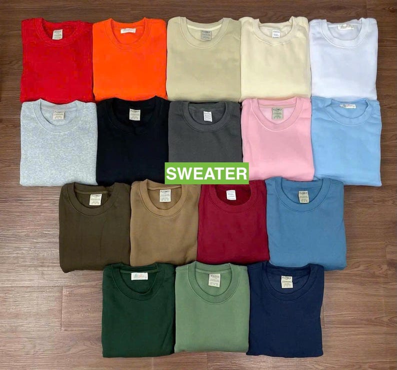 May include: A collection of folded crew neck sweaters in various colors, including red, orange, beige, white, light blue, gray, black, dark gray, pink, olive green, brown, burgundy, teal, green, and navy. The word "SWEATER" is displayed in green.
