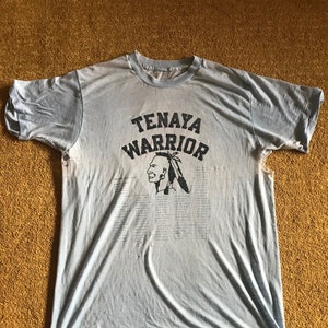 May include: A light blue t-shirt with a faded print of a Native American warrior's head with the text "Tenaya Warrior" above it.