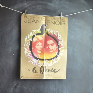 May include: A vintage movie poster for the film "Le Fleuve" by Jean Renoir. The poster features a gold background with a stylized image of a fig, and two people's faces are visible inside the fig. The text on the poster reads "Le Chef D'Oeuvre de Jean Renoir" and "Le Fleuve".