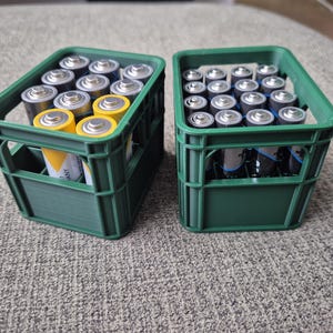 Könnte beinhalten: Zwei grüne Plastikkisten gefüllt mit AA-Batterien. Eine Kiste enthält gelbe und schwarze Batterien, die andere silberne Batterien.