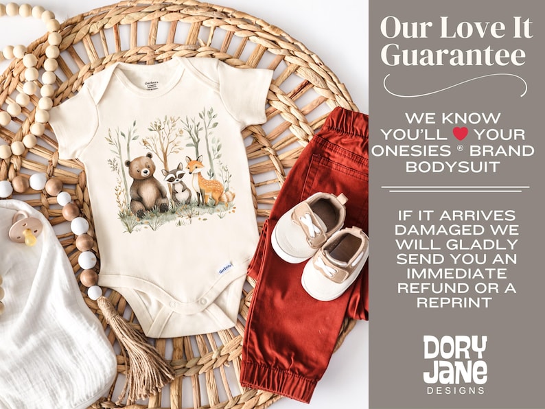 May include: A cream-colored onesie with a watercolor illustration of a bear, raccoon, and fox in a forest setting. The onesie is on a woven wicker surface with a wooden bead garland and a pair of red pants and beige shoes.