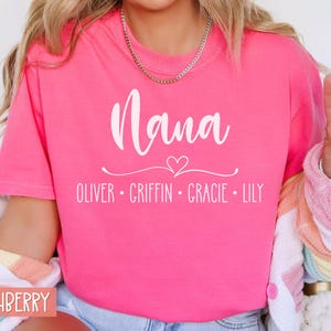 May include: Pink t-shirt with the text "Nana" in white cursive font, a small white heart, and the names "Oliver, Griffin, Gracie, Lily" in white text below.