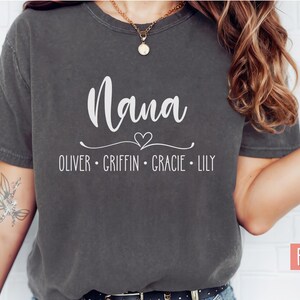 May include: A dark gray t-shirt with the word "Nana" in white text and a heart design. Below the word "Nana" are the names "Oliver, Griffin, Gracie, Lily" in white text.