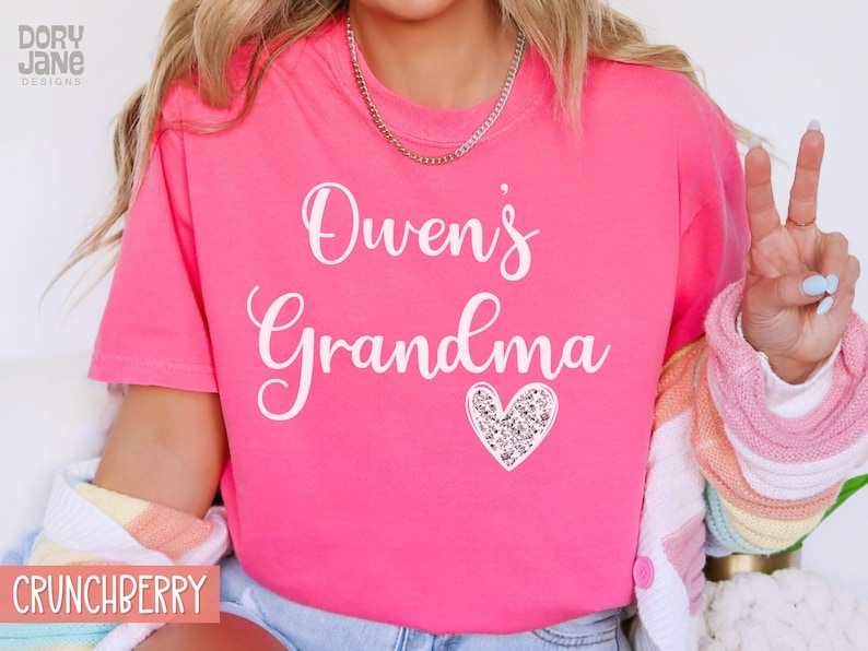 May include: Pink t-shirt with the text "Owen's Grandma" in white lettering and a sparkly silver heart.