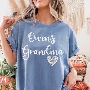 May include: A blue jean t-shirt with the text "Owen's Grandma" in white lettering and a sparkly silver heart.