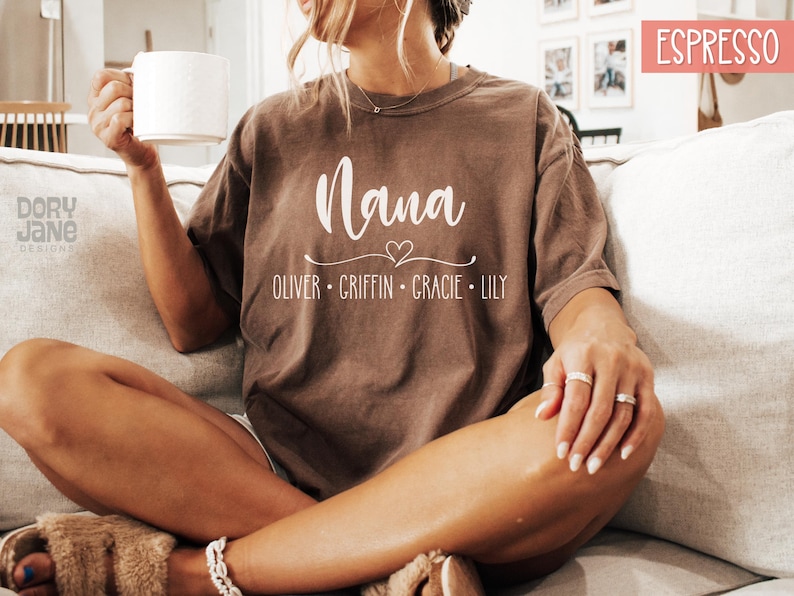 May include: A brown t-shirt with the word "Nana" and a heart design. Below the word "Nana" are the names "Oliver, Griffin, Gracie, Lily".
