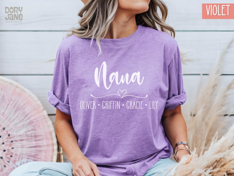 May include: A purple t-shirt with the text "Mama" in white cursive lettering. Below the text is a small heart and the names "Oliver, Griffin, Gracie, Lily" in white.